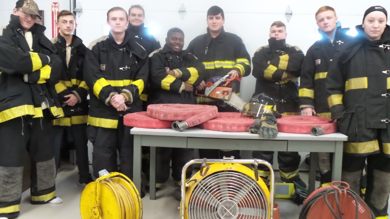 KACC Fire-Rescue-EMR Students wearing the donated Turnout Gear and standing in front of donated equipment.